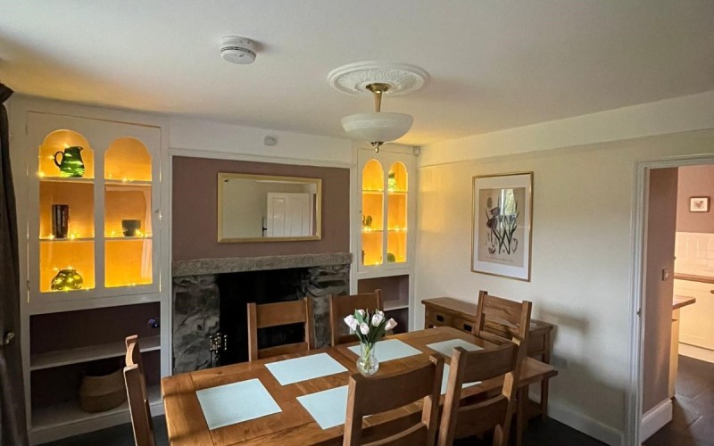 Harford House Dining Room Dining room floor is uneven but level natural slate leading to the kitchen with a level tiled floor.  Doors are standard width.  There is natural light from the south facing window, overhead lighting with supplementary lighting to the alcoves by the log burner.